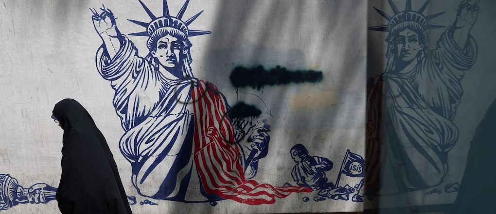 Una donna cammina davanti a un murale anti-americano a Teheran via REUTERS