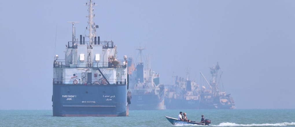 Una piccola imbarcazione a motore passa accanto a navi ancorate nello Stretto di Hormuz APN