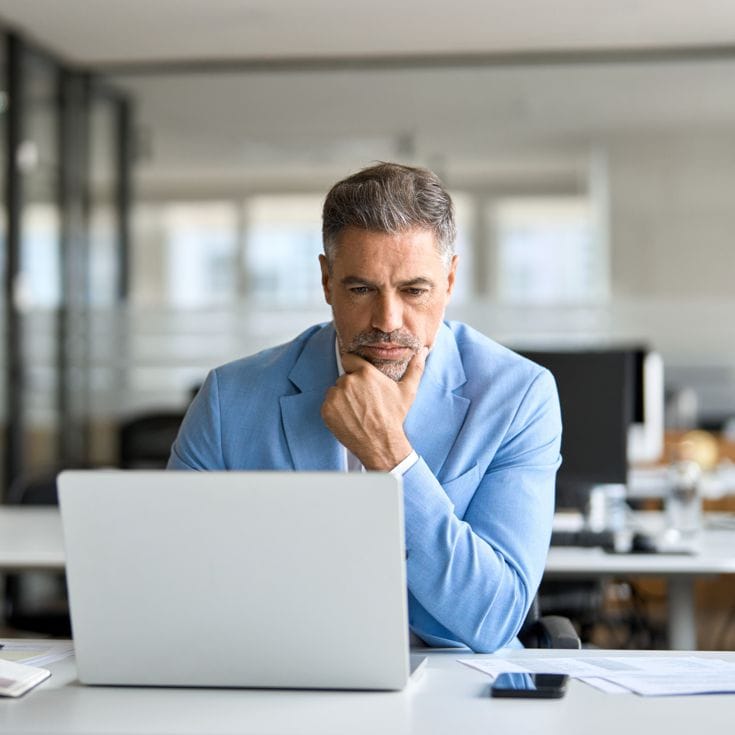 Busy serious middle aged professional business man financial investor, 50 year old senior businessman executive wearing suit using laptop computer working on investment project sitting at office desk. insta_photos - stock.adobe.com