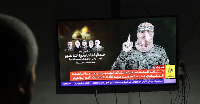 I palestinesi sfollati seguono la conferenza stampa del nuovo portavoce delle Brigate Ezzedine Al-Qassam, nel campo profughi di Bureij, nella parte centrale della Striscia di Gaza, il 29 dicembre 2025.  (Foto di Eyad Baba / AFP) AFP
