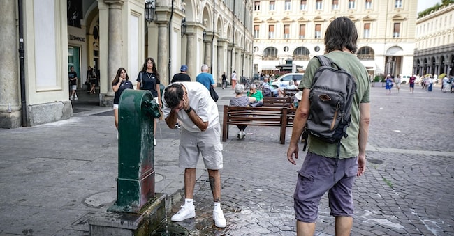 Una persona si rinfresca ad una fontana detta Turet per combattere il caldo estivo in piazza San Carlo. Torino (ANSA/TINO ROMANO)