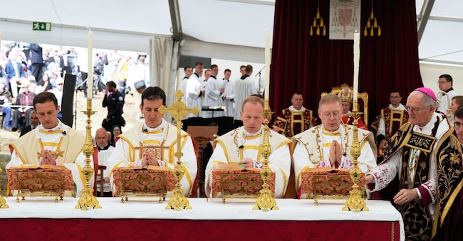 Da sinistra, i padri Marc Hanappier, Michel Poinsinet de Sivry, Michael Goldade e Pascal Schreiber, affiancati a destra dal vescovo Bernard Fellay, pregano durante la cerimonia di consacrazione episcopale in un tendone allestito  (APN)