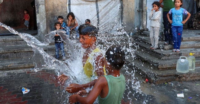 Bambini palestinesi sfollati giocano nell'acqua mentre trovano rifugio in una scuola in una giornata torrida, a Khan Younis, nella parte meridionale della Striscia di Gaza, il 1° luglio 2026. REUTERS/Ramadan Abed REUTERS