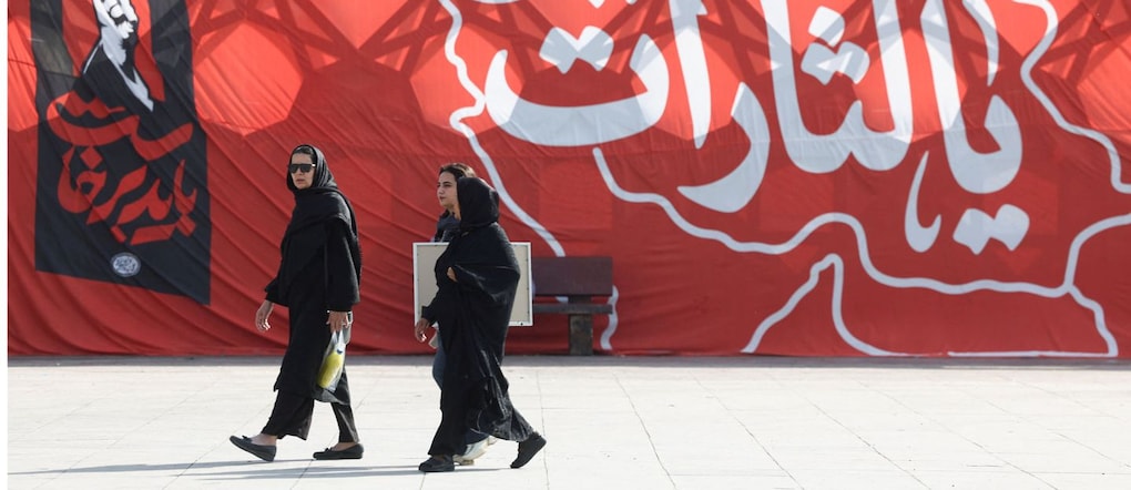 La gente passa davanti a uno striscione con l'immagine del pugno alzato del defunto Leader Supremo, l'Ayatollah Ali Khamenei, in Piazza dell'Imam Hussein a Teheran, in Iran, il 12 luglio 2026. Majid Asgaripour/WANA (West Asia News Agency) via REUTERS via REUTERS