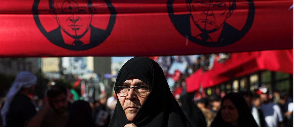 Una donna si trova sotto uno striscione contro il presidente degli Stati Uniti Donald Trump e il primo ministro israeliano Benjamin Netanyahu, mentre i partecipanti al funerale si radunano nel giorno della sepoltura del defunto leader supremo iraniano, l’ayatollah Ali Khamenei, ucciso il 28 febbraio in seguito a attacchi aerei israeliani e statunitensi, nel momento culminante di un funerale di massa, a Mashhad, in Iran, il 9 luglio 2026.  via REUTERS