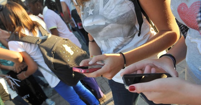 Un gruppo di adolescenti consulta il proprio cellulare. ANSA/ SILVI ANSA