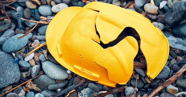 Cracked work helmet on the floor covered with pebble stones. Concept of work accident. Cagkan - stock.adobe.com