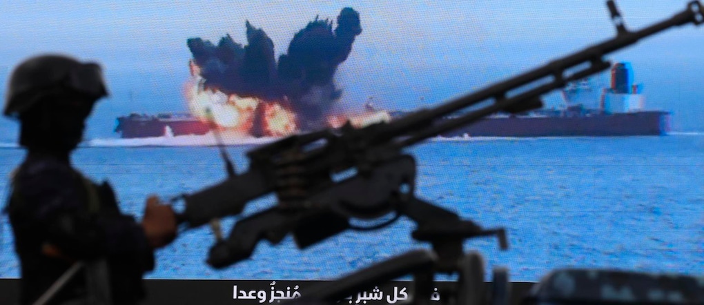Un combattente Houthi con una mitragliatrice accanto a un cartellone digitale che mostra una nave sotto attacco nel Mar Rosso, durante una manifestazione di solidarietà con Hezbollah dopo il cessate il fuoco tra Libano e Israele, a Sana’a EPA