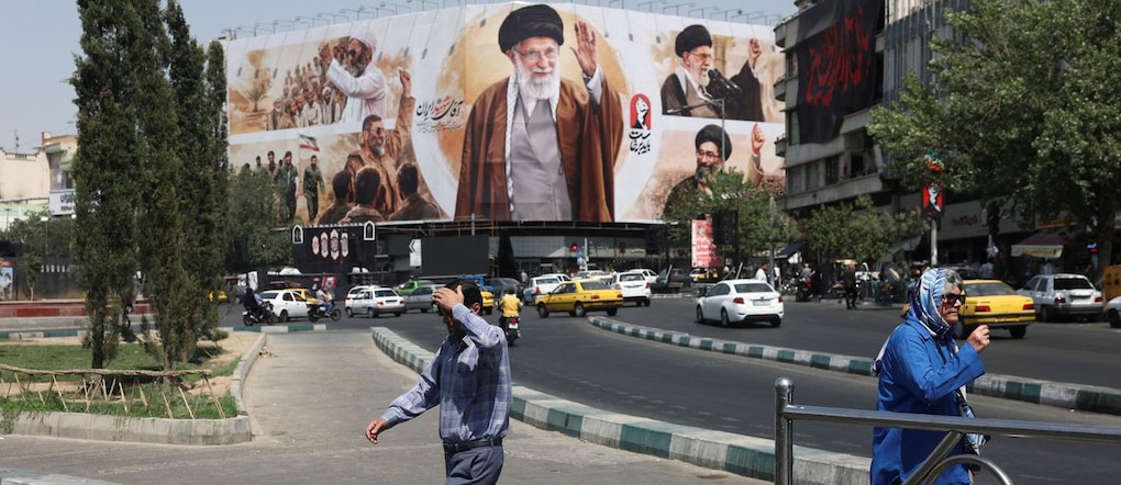 A Teheran, in Iran,alcune persone passano davanti a un cartellone pubblicitario con le immagini del defunto leader supremo iraniano, l’ayatollah Ali Khamenei. Majid Asgaripour/WANA (West Asia News Agency) via REUTERS  via REUTERS