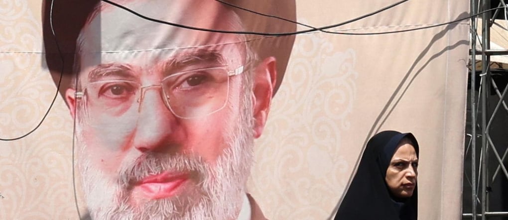 Una donna iraniana passa davanti a un manifesto che mostra la nuova Guida Suprema dell’Iran, l’Ayatollah Mojtaba Khamenei, a Teheran. EPA