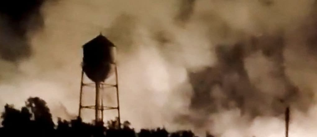 In questa immagine fissa tratta da un video diffuso sui social media il 22 luglio 2026, una torre dell’acqua si staglia contro il fumo che si alza da un incendio a seguito di un attacco missilistico a Behbahan, nella provincia del Khuzestan, in Iran. SOCIAL MEDIA via REUTERS