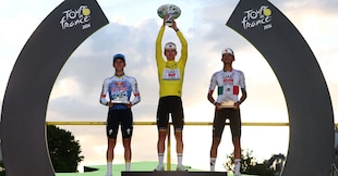 Ciclismo - Tour de France - 21ª tappa - Parigi, Francia - 26 luglio 2026 Tadej Pogacar dell'UAE Team Emirates XRG festeggia sul podio indossando la maglia gialla dopo aver vinto il Tour de France, affiancato da Isaac Del Toro dell'UAE Team Emirates XRG, che indossa la maglia bianca, e da Red Bull - Remco Evenepoel della BORA - hansgrohe REUTERS/Gonzalo Fuentes REUTERS