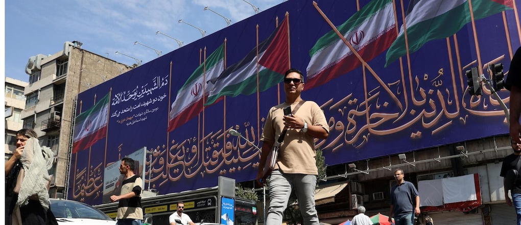 Una strada di Teheran con un poster che raffigura le bandiere di Iran e Palestina  EPA
