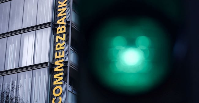 I semafori illuminano il logo della Commerzbank in una filiale, mentre l’italiana UniCredit lancia un’offerta non richiesta per aumentare la propria quota nella Commerzbank oltre il 30%, superando così la soglia obbligatoria del 30% prevista dalla legge tedesca in materia di acquisizioni, a Colonia, Germania, il 16 marzo 2026. REUTERS/Thilo Schmuelgen/Foto d'archivio REUTERS