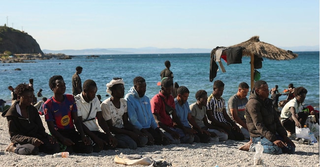 I migranti pregano mentre attendono su una spiaggia di Ceuta, in Spagna, a seguito delle traversate di massa con esiti mortali compiute da migranti a piedi e via mare dal Marocco verso il territorio spagnolo, il 3 agosto 2026. REUTERS/Violeta Santos Moura REUTERS