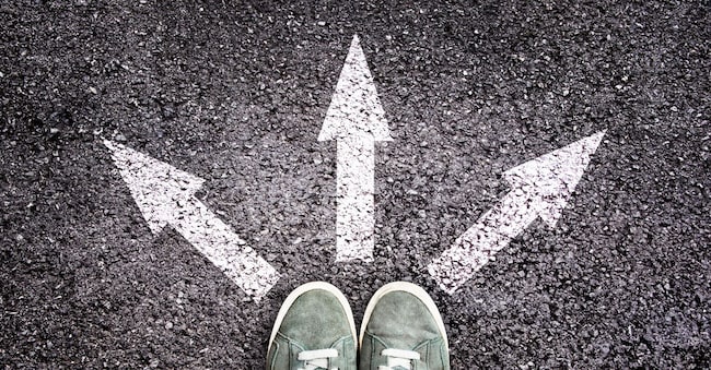 Shoes and arrows pointing in different directions on asphalt floor Delphotostock - stock.adobe.com