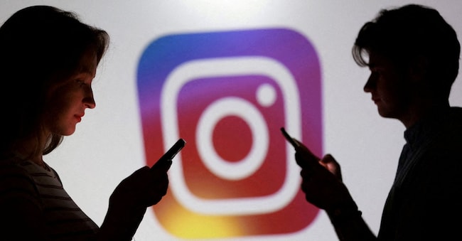 In questa illustrazione realizzata l'11 settembre 2025, alcuni adolescenti posano per una foto tenendo in mano gli smartphone davanti al logo di Instagram. REUTERS/Dado Ruvic/Illustrazione/Foto d'archivio REUTERS