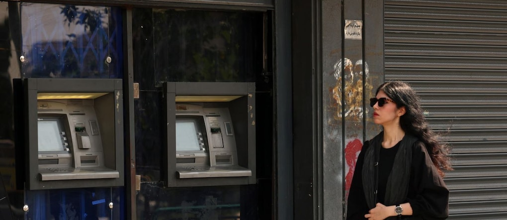 Una donna iraniana cammina accanto a un bancomat in una strada del centro di Teheran, in Iran, il 13 agosto 2026. Le tensioni tra l’Iran e gli Stati Uniti rimangono elevate, mentre persistono le rivendicazioni contrapposte sul controllo del traffico marittimo nello Stretto di Ormuz.  EPA/ABEDIN TAHERKENAREH EPA