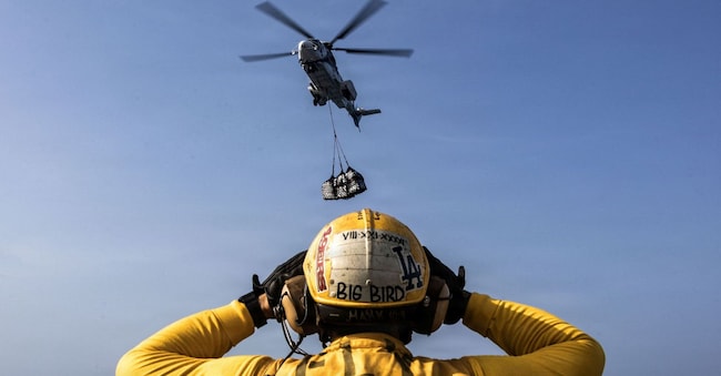 Un marinaio americano assiste un Eurocopter  Super Puma dalla pista della  nave USS Abraham Lincoln  via REUTERS