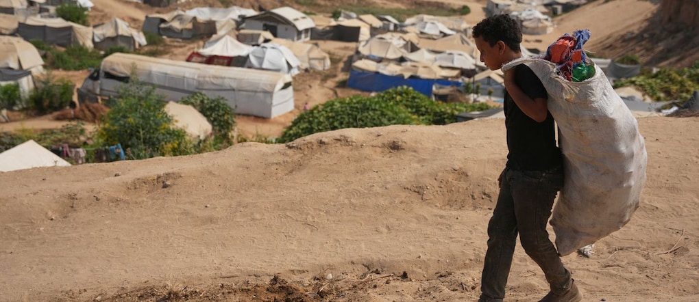 Un ragazzino palestinese si allontana da una discarica dopo aver raccolto materiali da utilizzare come combustibile per cucinare, a causa della carenza di gas da cucina, a Deir al-Balah, nella Striscia di Gaza centrale (Foto AP/Abdel Kareem Hana) APN