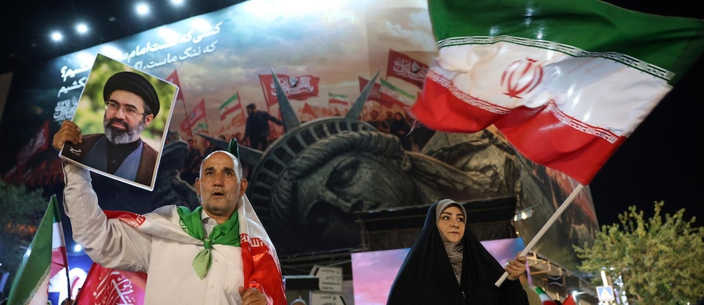 Un uomo iraniano (a sinistra) tiene in mano un ritratto della Guida Suprema, l'ayatollah Mojtaba Khamenei, durante una manifestazione notturna contro gli Stati Uniti a Teheran, in Iran, il 26 agosto 2026, in seguito all'annuncio da parte di Washington di nuove sanzioni. Teheran ha promesso di reagire dopo che il segretario al Tesoro statunitense Scott Bessent, agendo su indicazione del presidente Donald Trump, ha lanciato l’«Operazione Economic Outcast», una campagna economica volta a tagliare i collegamenti finanziari globali dell’Iran. EPA/ABEDIN TAHERKENAREH EPA