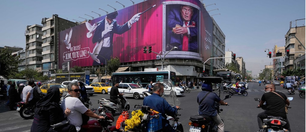 Nel centro di Teheran, in Iran, alcuni veicoli passano davanti a un cartellone pubblicitario che raffigura il presidente degli Stati Uniti Donald Trump all’interno di un container per il catering, insieme a un mago e alla scritta «Nessun trucco! Se sbatti le palpebre, sei sparito» (APN)