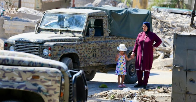 Una donna e una bambina in piedi accanto a veicoli militari libanesi a Zawtar al-Gharbiya, nel sud del Libano, il 5 agosto 2026. Zawtar al-Gharbiya è una delle zone pilota designate nell’ambito dell’accordo di cessate il fuoco tra Libano e Israele, dalla quale le forze israeliane si sono ritirate.   (EPA/Stringer)