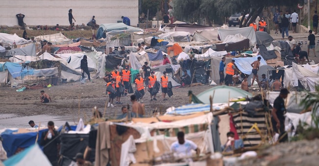 Mercoledì 2 settembre 2026, alcuni migranti sono in piedi vicino alle loro tende sulla spiaggia di El Trampolín, nell’exclave spagnola di Ceuta. (Foto AP/Francis González) AP Photo/Francis González