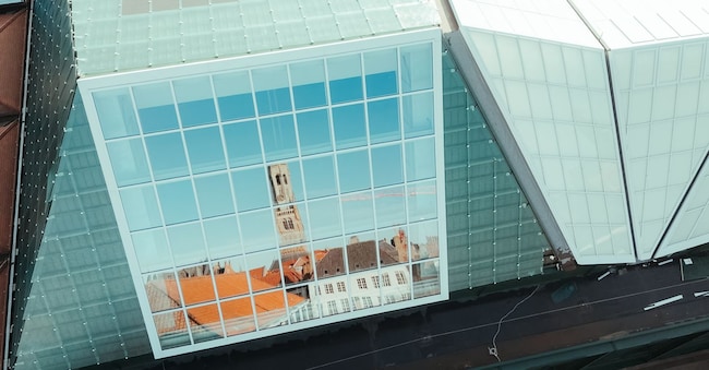 La torre del Belfry si specchia sulle vetrate di Brusk, il grande centro di arte contemporanea appena inaugurato a Bruges (Belgio).