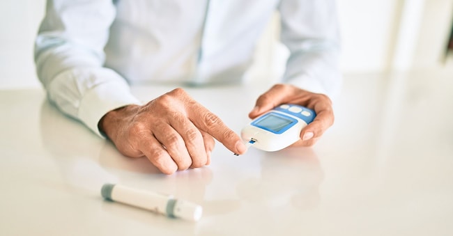 Un uomo affetto da diabete che utilizza un glucometro a insulina con un campione di sangue prelevato dal dito (Adobe Stock)