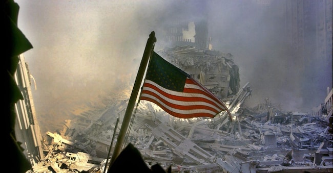 La bandiera americana sventola tra le macerie del World Trade Center a New York, alcune ore dopo l'attentato alle Torri Gemelle crollate a causa dell'impatto di due aerei dirottati dai terroristi islamici sulle Twin Towers, l'11 settembre 2001, New York. ANSA/ EPA/C'sar De Luca ANSA