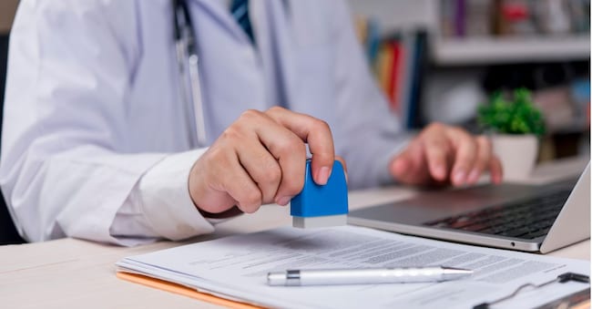 doctor is stamping an important medical document, indicating the confirmation of information, approval of treatment, issuance of a certificate, professional and legal work. khunkornStudio - stock.adobe.com