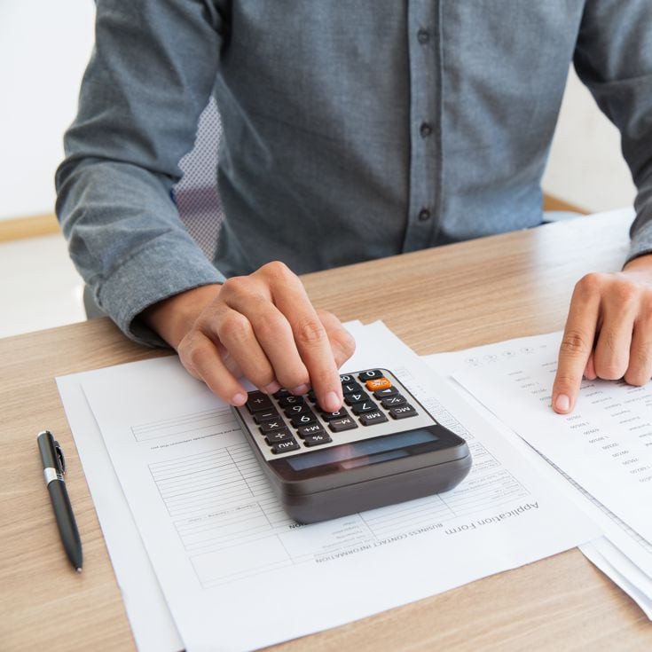 Close-up of unrecognizable man working with financial data. He using calculator and examining document. Financial inspector holding examination. Paperwork or finance concept