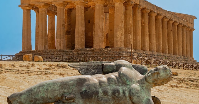 In primo piano, Icaro caduto, di Igor Motoraj. Sullo sfondo, il Tempio della Concordia, nella Valle dei Templi ad Agrigento  Adobestock