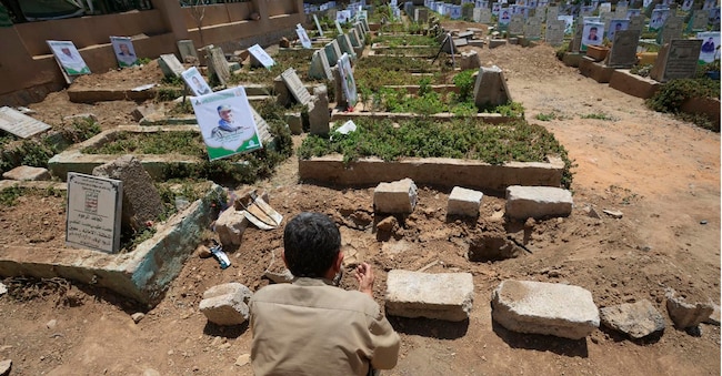 Un uomo prega davanti all’ultima tomba allestita in un cimitero dedicato alle vittime dei combattimenti in Yemen EPA/YAHYA ARHAB