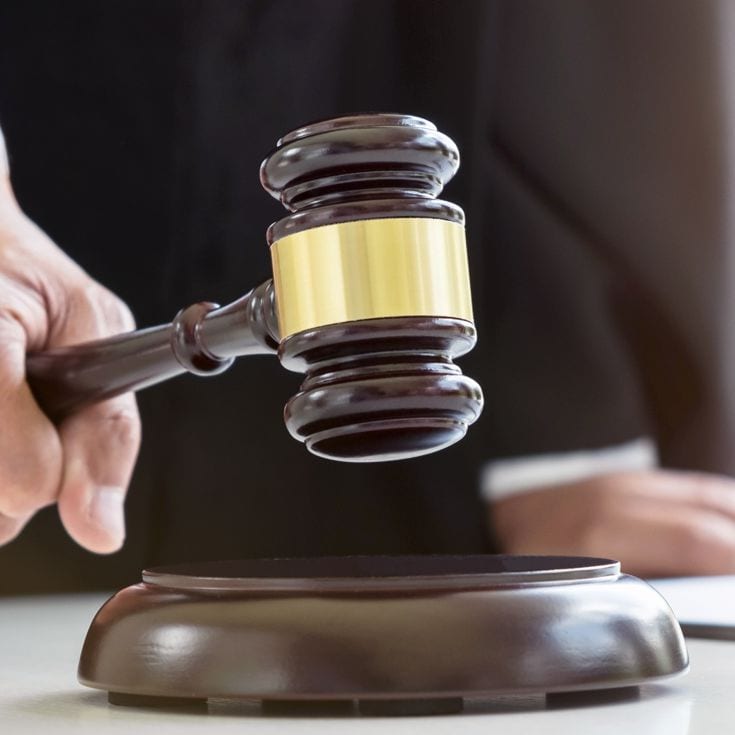 Close up of Male lawyer or judge hand's striking the gavel on sounding block, working with Law books, report the case on table in modern office, Law and justice concept. Freedomz - stock.adobe.com
