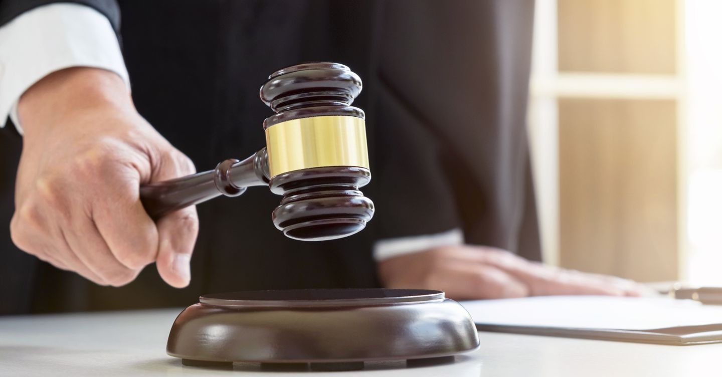 Close up of Male lawyer or judge hand's striking the gavel on sounding block, working with Law books, report the case on table in modern office, Law and justice concept. Freedomz - stock.adobe.com