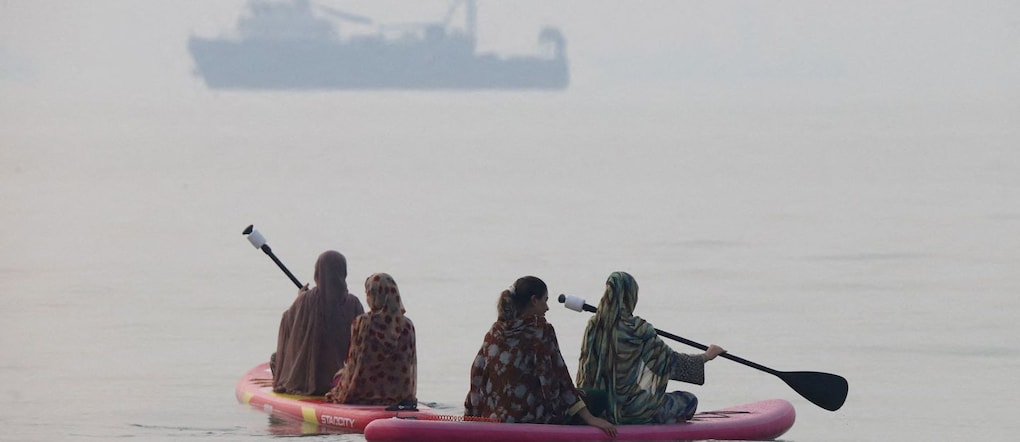 Alcune donne utilizzano delle tavole da paddleboard, mentre in lontananza si intravede un'imbarcazione nello Stretto di Hormuz, nei pressi della spiaggia di Bandar Abbas, in Iran, il 6 ottobre 2026 via REUTERS