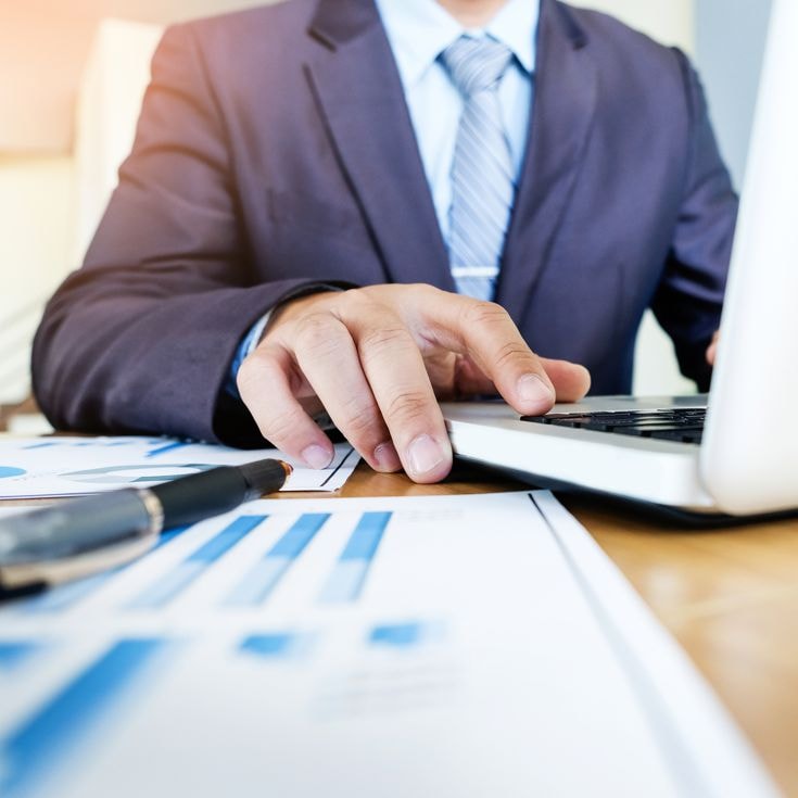 Working process startup. Businessman working with new finance project at office with laptop, tablet and graph data documents on his desk
