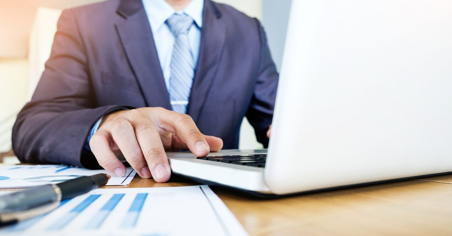Working process startup. Businessman working with new finance project at office with laptop, tablet and graph data documents on his desk