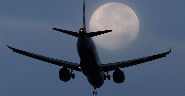 A passenger plane passes in front of the moon as it makes its landing approach to Heathrow Airport, which said during the weekend that the third runway may not be operational until 2039, in London, Britain, September 28, 2026.  REUTERS/Toby Melville       TPX IMAGES OF THE DAY REUTERS