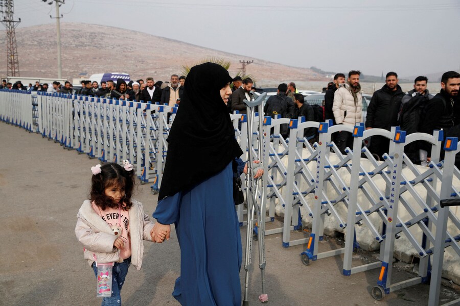 Una donna supera le barriere di sicurezza mentre i migranti siriani aspettano in fila per attraversare il confine con la Siria, dopo che i ribelli siriani hanno rovesciato il presidente Bashar al-Assad, al valico di frontiera di Cilvegozu nella provincia di Hatay, Turchia (REUTERS)