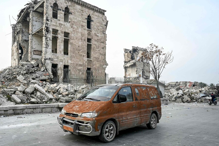 Un veicolo passa oltre le macerie di un edificio danneggiato nella Cittadella di Aleppo, nel nord della Siria, l’11 dicembre 2024. I ribelli guidati dagli islamisti hanno preso la capitale siriana Damasco in un’offensiva lampo l’8 dicembre, estromettendo il presidente Bashar al-Assad e ponendo fine a cinque decenni di governo Baath nel paese. (AFP)