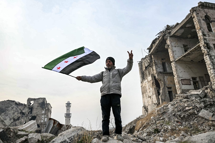 Un uomo sventola una bandiera dell’opposizione siriana nella Cittadella di Aleppo, nel nord della Siria, l’11 dicembre 2024. L’8 dicembre, i ribelli guidati dagli islamisti hanno preso la capitale siriana Damasco con un’offensiva lampo, rovesciando il presidente Bashar al-Assad e ponendo fine a cinque decenni di governo Baath nel paese (AFP)