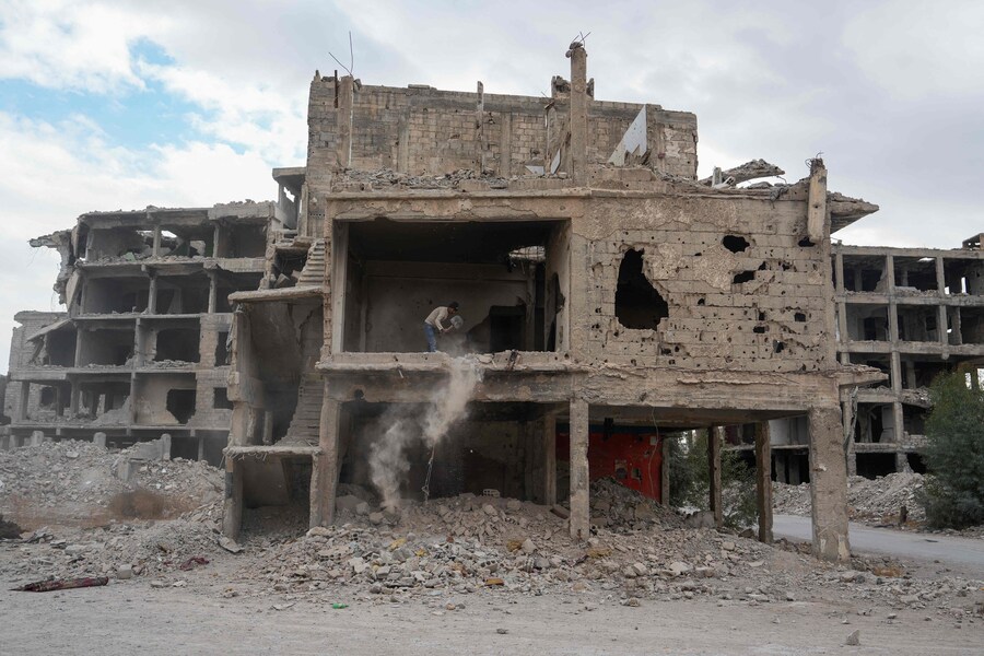 Un uomo rimuove macerie e detriti da una casa danneggiata nel campo di Yarmuk. (MUHAMMAD HAJ KADOUR / AFP)