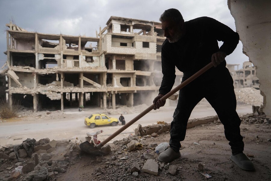 Un uomo rimuove macerie e detriti da una casa danneggiata nel campo di Yarmuk. (MUHAMMAD HAJ KADOUR / AFP)