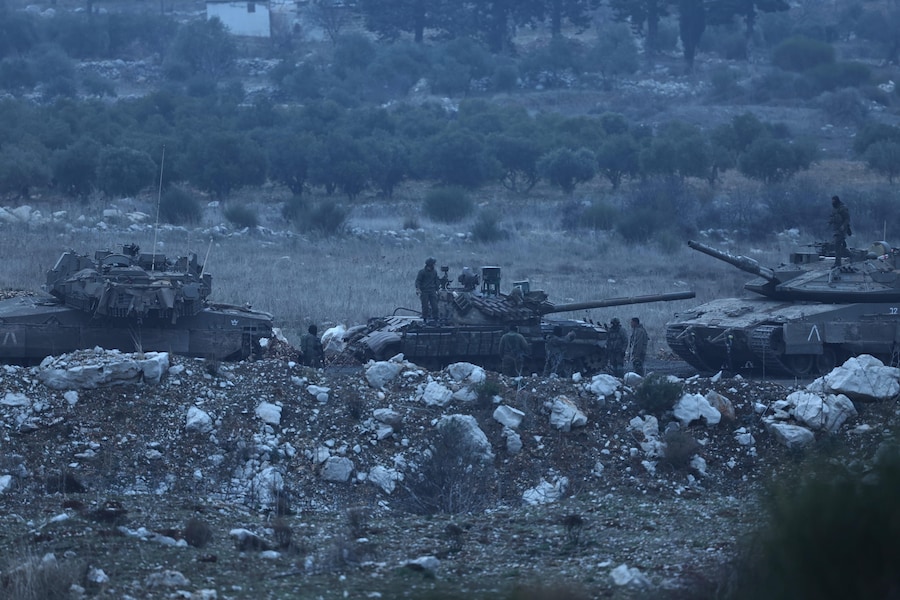 Soldati israeliani in piedi vicino a un carro armato siriano T-72 all’interno della zona cuscinetto prima di trasferirlo in Israele. (EPA/ATEF SAFADI)