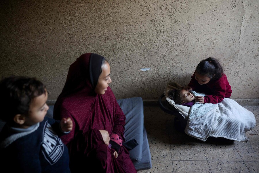Parenti di una bambina palestinese di cinque anni che soffre di malnutrizione la circondano in un rifugio in cui vivono dopo essere stati sfollati dalla guerra. (Eyad BABA / AFP)
