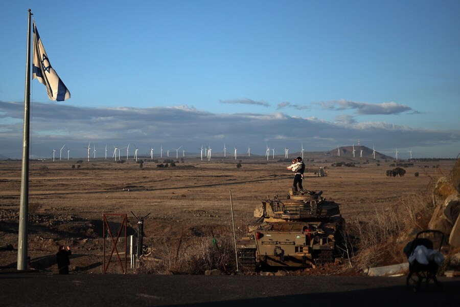 Un ebreo ortodosso israeliano in cima a un carro armato militare abbandonato vicino al confine siriano a Tel A Saki (EPA/ATEF SAFADI)