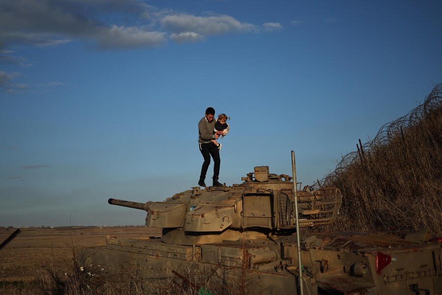 Un ebreo ortodosso israeliano in cima a un carro armato militare abbandonato vicino al confine siriano a Tel A Saki. (EPA/ATEF SAFADI)